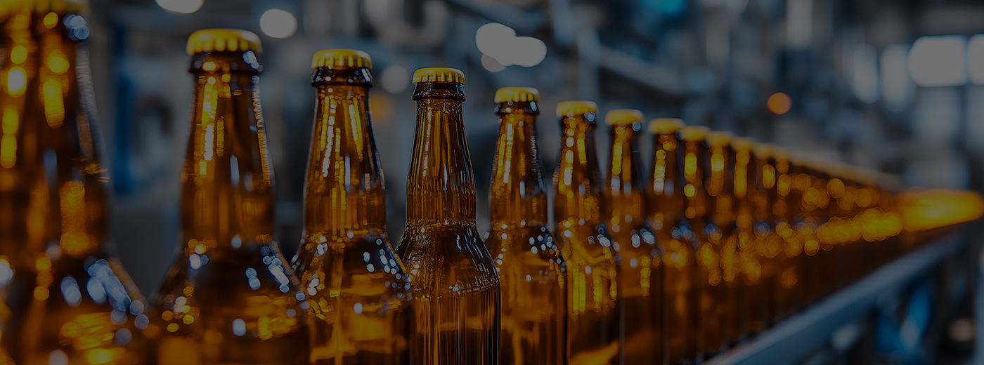 A row of amber glass bottles on an assembly line in a brewery, showcasing the manufacturing and production process. 