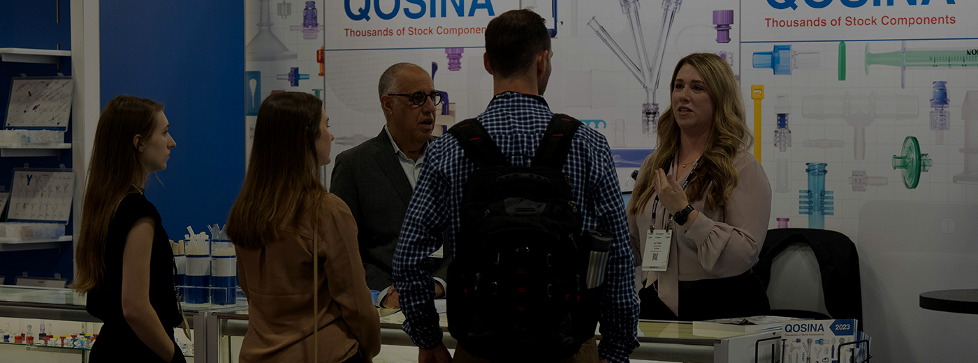 Attendees gather around a booth labeled "Gossamer," as an exhibitor demonstrates their product to the crowd