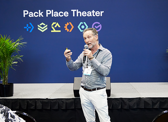 A male speaker presenting in front of a conference audience